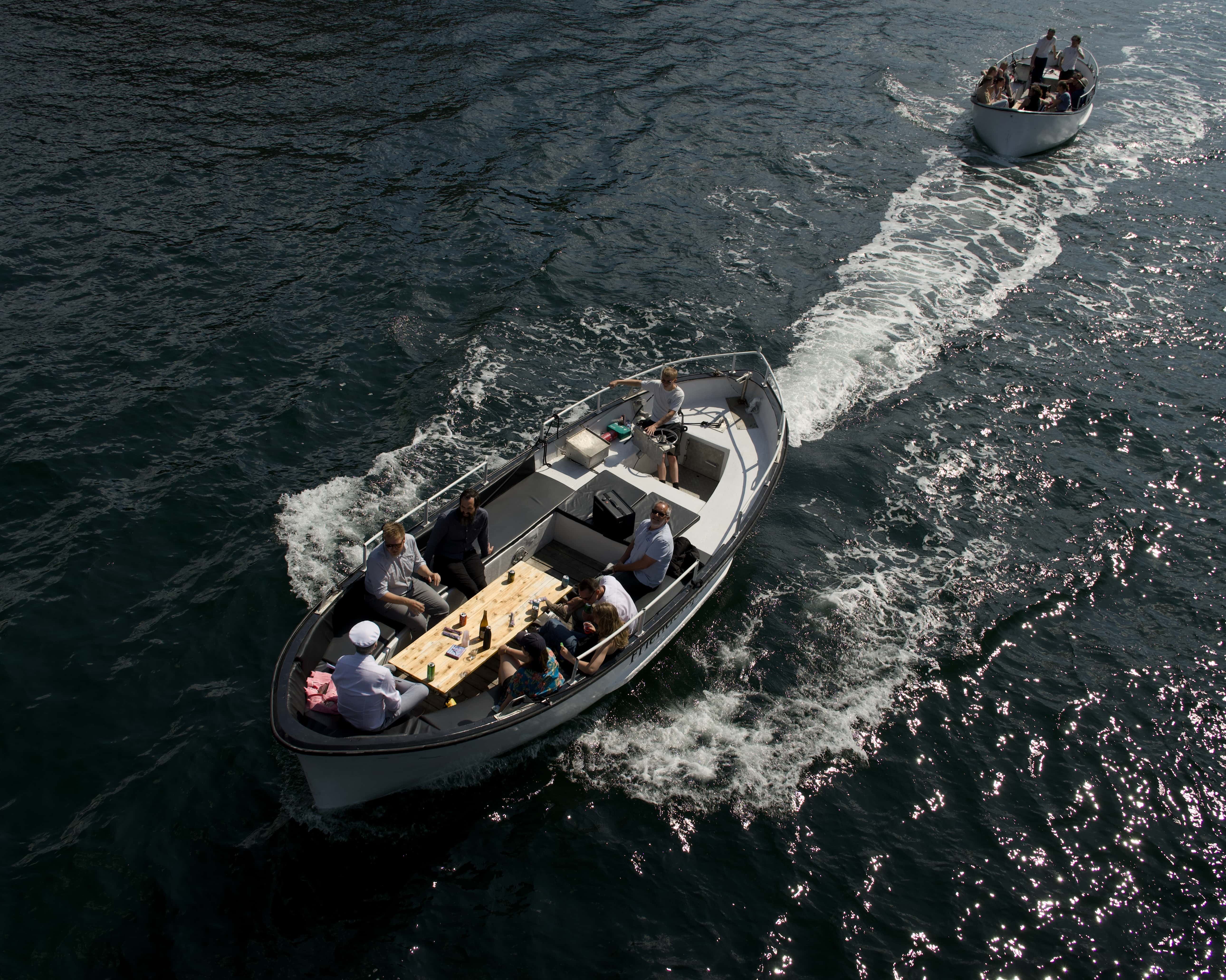 A photo of two small motorboats taken from above. The men inside are partying and drinking.